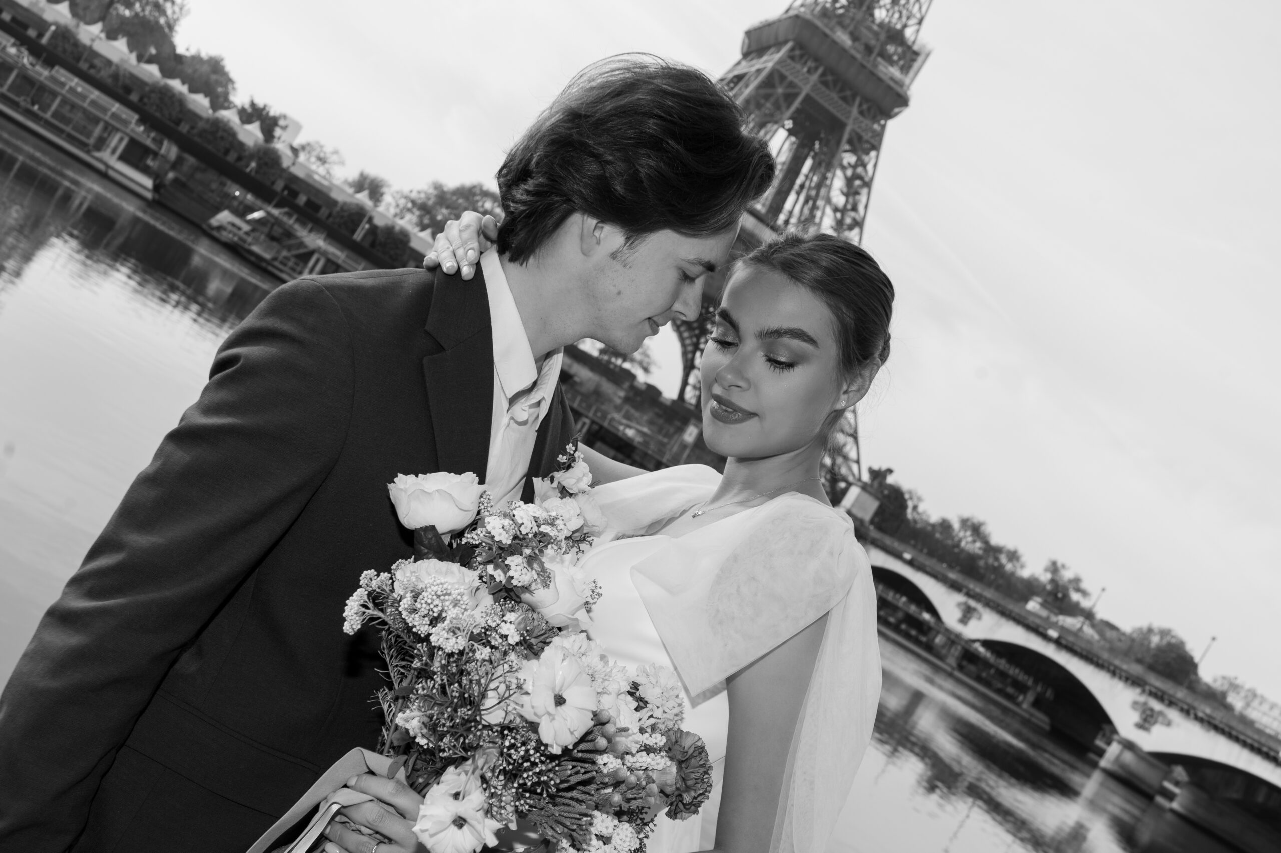 Ein Paar umarmt sich mit einem Blumenstrauß in der Nähe des Eiffelturms, ihre Liebe leuchtet wie ein Märchen bei Dornröschen, während sie am Fluss in Paris stehen.