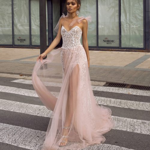 Frau in einem durchsichtigen, hellrosa Spitzenhochzeitskleid mit hohem Schlitz, stehend auf einem Steg - ein eleganter Look aus dem Brautatelier bei Dornröschen in Nürnberg.